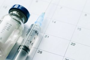 The vial with vaccine and syringe on calendar