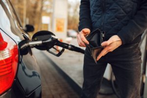 Man with empty purse on gas station, fuel filling